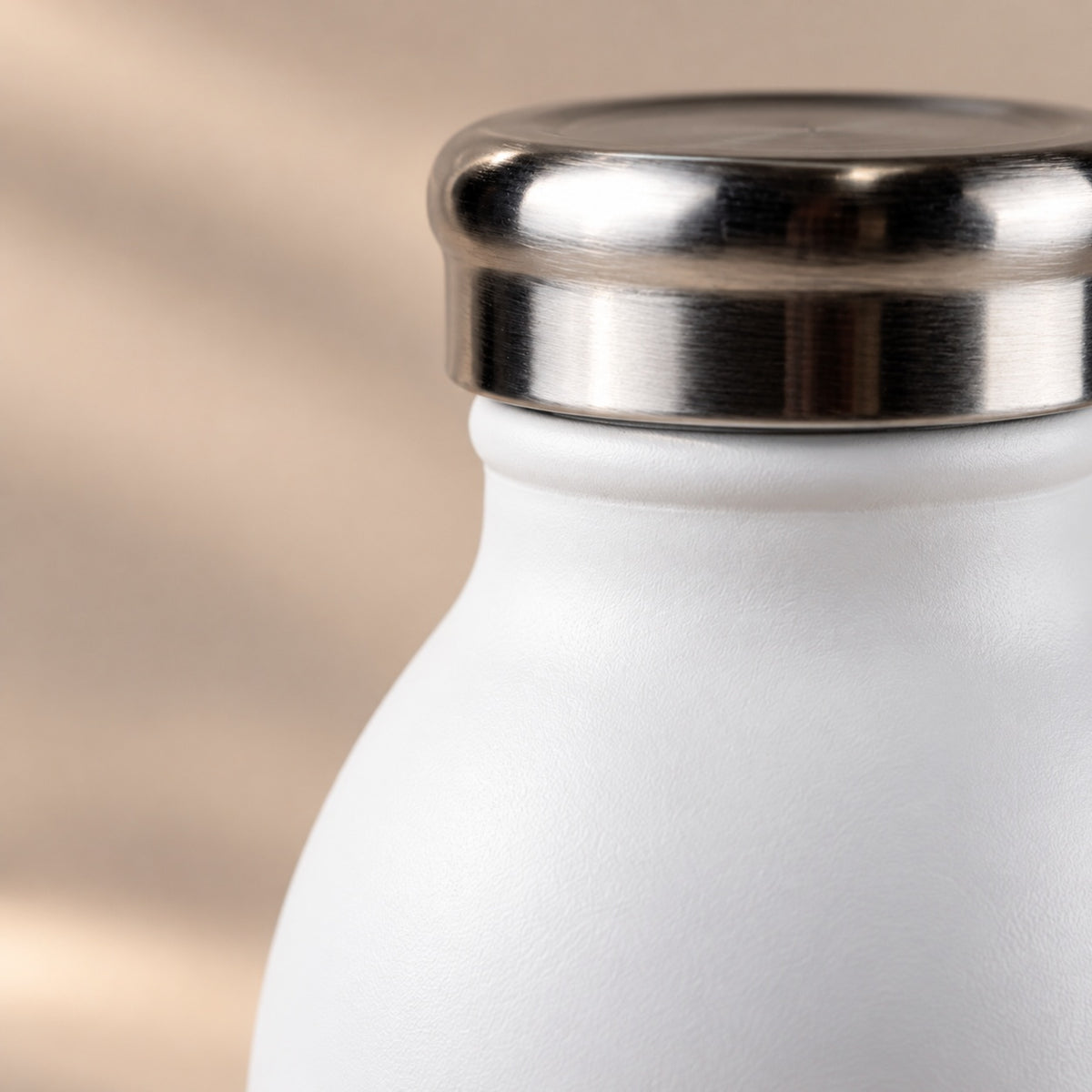 Close-up of the polished stainless steel cap and matte white finish